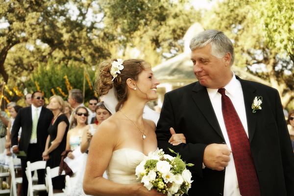 the beautiful bride and her father looking at each other as they walk down the aisle during the outdoor ceremony - photo by North Carolina based wedding photographers Cunningham Photo Artists